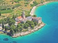 Niewątpliwie Chorwaci mają się czym pochwalić. Piękne widoki, sympatyczna atmosfera, liczne atrakcje turystyczne, to wszystko sprawia, że tłumnie ściągają tu na wczasy turyści z całego świata. Jakby tego wszystkiego było mało, w skład Chorwacji wchodzi również wyspa, która może się poszczycić jedną z najpiękniejszych plaż na Adriatyku. Która to wyspa? Wyspa Brač, na której południowym wybrzeżu znajduje się doskonale znana turystom miejscowość Bol.


Historia


Historia tego jednego z najstarszych miast na wyspie, jest ściśle z nią związana. Wraz z przechodzeniem wyspy Brač, z rąk do rąk, również ta osada, trudniąca się głównie rybołówstwem, rolnictwem i uprawą winą, dostawała się pod panowanie możnych. Pierwsze ślady obecności ludzkiej na wyspie Brač sięgają epoki kamienia łupanego. Jak twierdzą naukowcy, w IV w. p. n.e. tereny te zamieszkiwało plemię Dalmata. Po okresie greckiej kolonizacji, na wyspie nie pozostało zbyt wiele śladów, w przeciwieństwie do okresu rzymskiego. Rzymianie odkryli tu złoża cennego białego kamienia wapiennego, który służył do budowy licznych osiedli. Wyspa znajdowała się również pod wpływem Wenecji, jednak dopiero znajdując się pod władzą Francji, podniósł się znacznie poziom życia na wyspie Brač. Jednak w okresie wojen światowych, ludność wyemigrowała, a wyspa uległa dużemu zniszczeniu. Po wyzwoleniu się z okupacji faszystowskiej, wyspa wraz z miastem Bol została wcielona do Jugosławii. Po jej upadku, w 1991 roku, wyspa Brač oficjalnie została włączona w tereny Chorwacji.


Atrakcje turystyczne i wycieczki


Miasto Bol, jak i jego okolice obfitują w atrakcje turystyczne. Jeżeli chcemy kulturalnej rozrywki, koniecznie musimy tu przyjechać na wczasy w okresie letnim. Wtedy bowiem odbywa się letni festiwal miasta Bol, podczas którego można codziennie podziwiać występy trup teatralnych, śpiewaków czy muzyków. Niewątpliwie warto skorzystać z umiejscowienia Bolu, mianowicie u podnóża najwyższego szczytu wysp Adriatyku, Vidowej Gory (778 m. n. p.m). Piesza wędrówka na szczyt dostarczy nam niezapomnianych wrażeń widokowych. Warto również poświęcić czas na wycieczkę do miejsca zwanego Pustynia Blaca. Jest to jedna z oryginalniejszych ciekawostek etnologicznych na całej wyspie. Jest to kompleks architektoniczny zbudowany przez mnichów właśnie na terenie kamiennej pustyni. Skoro jesteśmy już przy kamieniach i ciekawostkach etnologicznych warto zwiedzić Smoczą Jamę (Drahonijna Spilja, Zmajeva spilja). Znajdziemy ją pod klifami Vidovej Gory, nad wsią Murvica. W środku tej nietypowej jamy możemy oglądać stare, kamienne rzeźby. Zwolennicy obiektów muzealnych powinni urządzić sobie wycieczkę do miejscowości Škrip. Znajduje się tutaj Regionalne Muzeum Wyspy Brač. Wybór miejsca nie powinien nikogo dziwić gdyż Škrip jest najstarszym miastem na wyspie. Pamiętając, że mieszkańcy wyspy żyją również z rybołóstwa, warto na własne oczy zobaczyć typową rybacka osadę. Taką możliwość da nam Postira. Można tam również zwiedzić zamek Lazarić z renesansową wieżą.


Plaże i sporty


Jednak zdecydowanie największą atrakcją Bolu jest najpiękniejsza plaża Adriatyku czyli Zlatni Rat. Jest to jedyna na świecie plaża, która jest położona prostopadle do nabrzeża. Zlatni Rat to również jedyna plaża, która zmienia swój kształt w zależności od wiatrów i fal. W zależności od warunków pogodowych, wchodzący w morze cypel o długości 158 metrów skierowany jest raz w lewą stronę, a raz w prawą. Jest to plaża żwirowa, o kształcie rogu, stąd też jej nazwa. To aż 5 kilometrów plaży, która podobno jako jedyna, zapewnia charakterystyczną, szybką, złocisto- brązową opaleniznę. Jej wizerunek często wykorzystywany jest na folderach i plakatach, a piękno jakim charakteryzuje się Zlatni Rat plaża, sprawia że przybywają tutaj również gwiazdy znane z pierwszych stron gazet. Zlatni Rat oferuje również mnóstwo możliwości do uprawiania sportów wodnych. Na plaży znajdziemy kilka szkół windsurfingu, gdyż miejsce to głównie upodobali sobie zwolennicy tego właśnie sportu. Oczywiście można również spróbować sił na nartach wodnych czy latając za łódką na spadochronie. Jednak plaża to nie jedyna możliwość uprawiania sportu. Możemy poszybować z Vidovej Gory, mając pod sobą całą wyspę. Możemy uprawiać wspinaczkę górską, lub poczuć się jak poszukiwacze skarbów, zagłębiając się w okolicznych jaskiniach.


Noclegi


Bol to miejscowość turystyczna, którą Chorwacja może się poszczycić. Mowa tutaj zarówno o atrakcyjności jak również o zapleczu turystycznym. Jeśli decydujemy się na wczasy w tym pięknym nadmorskim kurorcie, możemy liczyć na to, że miejscowość zaoferuje nam bogatą ofertę noclegową.


Kuchnia


Chorwacka kuchnia słynie z dań rybnych, nic więc dziwnego, że zwłaszcza na wyspach popularne są dania rybne, takie jak gęsta zupa rybna (brudet, brujet, brodet) lub czarny rizotto z kalmarnicy.


Klimat


Bol znajduje się w sferze klimatu śródziemnomorskiego i może się poszczycić aż 134 dniami bezchmurnego nieba w roku. Jest to najbardziej słoneczny obszar Adriatyku - decydując się na wakacje w miejscowości Bol, na wyspie Brač, możemy być pewni że trafimy na większość słonecznych godzin - w roku jest ich w tym obszarze aż 2700. Jeśli do tego dodamy średnią temperaturę morza w wysokości 22°C, nie pozostaje nam nic innego jak rezerwować wakacje właśnie w tym miejscu.