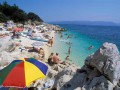 Podstawowe informacje


Słońce i spokój to główne zalety nadmorskiego kurortu Rabac, położonego w północnej części Chorwacji, na półwyspie Istria. Miejsce to jest najczęściej alternatywą dla zatłoczonych, gwarnych i przesyconych turystami kurortów znajdujących się w pobliżu. Podróżni chętnie się tutaj pojawiają, szukając przede wszystkim właśnie chwili wytchnienia. Niewielki Rabac oddalony jest około 3 km od Labina i stanowi świetne miejsce na zorganizowanie letnich wakacji na wschodnim wybrzeżu Istrii.


Historia


Pierwsi osadnicy pojawili się na terenie dzisiejszego miasteczka już przed wiekami - byli to przede wszystkim rybacy i drobni rzemieślnicy. Rozrastająca się osada stała się z czasem portem, do którego przybijały statki z cennymi kruszcami. Pierwszy hotel powstał już w 1889 r., z czasem wybudowano kolejne, coraz bardziej nowoczesne i komfortowe - tak po krótce powstał Rabac.


Atrakcje turystyczne


Zasadniczą atrakcją, której nie sposób pominąć podczas wakacji w Rabacu jest niewielki park rzeźby. Ponadto miasteczko jest prawdziwym rajem dla amatorów wodnego szaleństwa oraz innych form aktywnego wypoczynku. Na wszystkich zainteresowanych czekają możliwość żeglowania, surfowania, rejsy łodziami itp. W Rabacu można również zorganizować wycieczkę rowerową, spróbować swoich sił w tenisie ziemnym lub odwiedzić jeden z ośrodków sportowych - Prohaska oraz Oliwa.


Wycieczki fakultatywne


Podczas jednego z leniwych, upalnych popołudni można urządzić sobie pieszą wycieczkę do pobliskiego miasteczka Labin (około 3, 4 km na północny zachód od Rabaca). Kurort podzielony jest zasadniczo na 2 części: starsza leży na wzniesieniu i jest najbardziej atrakcyjna dla turystów, młodsza zajmuje tereny u stóp wzgórza i powstała w XIX wieku. Ze starego miasta roztaczają się wspaniale widoki na całe miasto i okolicę. Największą atrakcją w Labinie jest XI-wieczny kościół Narodzenia Najświętszej Marii Panny, łączący w sobie elementy stylu gotyckiego, romańskiego i renesansowego. Kilka kroków dalej natrafimy na Muzeum Miejskie, mające swoją siedzibę w XVIII-wiecznym pałacu. W muzeum (wstęp płatny) zgromadzono bogatą kolekcję dotyczącą historii miasta i okolicy, kultury mieszkańców, obrzędów, tradycyjnych strojów, przedmiotów codziennego użytku itp. Na przełomie lipca i sierpnia (to typowy okres wakacyjny, więc na pewno nie ominą nas jego atrakcje) w Labinie ma miejsce tzw. Labińskie Lato Kulturalne - zakrojony na szeroką skalę festiwal muzyczny.

Na wschodnim wybrzeżu Istrii ciekawym miejscem jest Raša, miasteczko o ogromnym zamiłowaniu do przemysłu (tutejszy region obfituje w złoża węgla), być może dlatego turyści nie pojawiają się tu na dłużej. Główną atrakcją w mieście jest kościół św. Barbary z charakterystyczną dzwonnicą, stanowiącą punkt orientacyjny w kurorcie.

Zwiedzanie wybrzeża możemy zakończyć nad zatoką Plominską, w mieście o podobnej nazwie - Plomin. Przed wiekami było to centrum Kvarneru (wówczas jeszcze pod nazwą Flanona). Dziś do głównych atrakcji turystycznych należy kościół św. Grzegorza z cennym przekładem głagolicy oraz parafialny kościół św. Jerzego (sv. Juraj). Ta niewielka osada położona na wzgórzu, pomiędzy zalesionymi terenami to doskonale miejsce na obserwację okolicy i zrobienie pamiątkowych zdjęć - widać stąd panoramę całej okolicy.

Nieco dalszą wycieczką fakultatywną może okazać się oddalony o około 25 km Park Narodowy Učka, znajdujący się we wschodniej części Półwyspu Istria, na obszarze górskim. Park jest świetnym miejscem dla miłośników pieszych wędrówek - wapienne szczyty nie są takie niedostępne, na jakie wyglądają. Do najważniejszych wzniesień należy Vojak (najwyższy - 1394 m n.p.m.), Sisol, Kremenjak, Brgud, Suhi Vrh oraz Plas. Na słynny Vojak prowadzi asfaltowa droga oraz pieszy szlak (wędrówka trwa około godzinę), ale najbardziej ekscytująca wyprawa czeka na tych, którzy zdecydują się na wyruszenie z Lovrany - wiodący stąd szlak jest dłuższy, prowadzi przez bardziej skaliste tereny, pośród zielonych lasów.

Popularnym wśród turystów miejscem jest leżący bardziej w głębi Istrii kurort Pazin (około 27 km od Rabacu), jedno z największych miast na półwyspie. To niezwykle malownicze miejsce znajduje się nad głęboką przepaścią - Jamą Fojba, nad którą z kolei wznosi się XI-wieczny zamek i stare miasto. Warto zajrzeć do Muzeum Etnograficznego (Etnografski Muzej, otwarte od poniedziałku do soboty, wstęp płatny) z ciekawymi zbiorami dotyczącymi historii Półwyspu Istria, lokalnej kultury oraz społeczności. Wśród obiektów sakralnych największą popularnością cieszy się kościół św. Mikołaja z II poł. XIII w. z późniejszą, XVIII-wieczną dzwonnicą. Zwiedzić tutaj można podziemia świątyni, gdzie uwagę turystów przyciąga zawsze herb Pazina - najstarszy z do dziś zachowanych. Ponadto w mieście warto odwiedzić Kościół Franciszkanów z końca XV w.

O rzut beretem i lądujemy w przepięknej mieścinie Beram, około 4 km od Pazina. Największą atrakcją jest tutaj kościół sv. Marije na Škrilinach, we wnętrzu którego znajdziemy imponujące, XV-wieczne freski. Planując odwiedzenie Beram warto wcześniej dowiedzieć się o możliwości otwarcia kościoła, ponieważ świątynia nie jest udostępniana turystom codziennie.


Noclegi


Rabac to spokojne miejsce, dlatego wielu wczasowiczów ulega zmyleniu. Nie brakuje tutaj nowocześnie urządzonych kompleksów wypoczynkowych, hoteli oraz apartamentów. Obok nich, lokalni mieszkańcy - gościnni Chorwaci - najczęściej oferują możliwość wynajęcia prywatnej kwatery. Tańsze koszty noclegu oraz kameralna atmosfera to główne atuty takiego miejsca.

Wśród ofert hotelowych na uwagę zasługuje np. 3-gwiazdkowy ośrodek Lanterna, położony blisko skalisto-żwirowej plaży. Pokoje wyposażone są w telewizję satelitarną, dodatkowym atutem może okazać się piękny widok na morze. Spośród pozostałych ofert noclegowych warto zapoznać się z hotelami: Narcis-Hedera, Mimosa, Apollo, Mediteran, Neptun, Marina, Castor oraz Pollux.