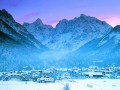 W Słowenii, nieopodal granicy austriackiej i włoskiej, w górskiej dolinie zwanej Zgornjesavska valley leży nowoczesne wczasowisko - Kranjska Gora. Świetnie poczują się tam nie tylko narciarze, ale również wszyscy Ci, którzy lubią aktywny wypoczynek na świeżym powietrzu. Alpy Julijskie czekają na amatorów białego szaleństwa oraz na każdego, kto poszukuje odrobiny relaksu na łonie natury.


Historia


Historia miejscowości Kranjska Gora sięga pierwszej połowy XIV wieku, kiedy w okolicy zaczęto wycinkę lasu, a powstałe w ten sposób pola zmieniano w pastwiska dla owiec i bydła. Ciekawe legendy krążą o pobliskim miasteczku Podkoren. Znajduje się tam wiele zabytków w tym m.in. późno gotycki kościół św. Andrzeja. Podczas I wojny światowej jeńcy rosyjscy wybudowali nad doliną Zgornjesavska valley drogę na wysokości ponad 1600 metrów! Kurort rozsławiły jednak dopiero konkursy narciarskie na pobliskiej skoczni mamuciej w Planicy. Już pod koniec lat pięćdziesiątych minionego stulecia wybudowano tu pierwsze kolejki i profesjonalne wyciągi. 


Zakwaterowanie


W Kranjskiej Górze znajdują się zarówno hotele, motele, jak i schroniska młodzieżowe. Istnieje również możliwość wynajęcia pokoju w kwaterach prywatnych. Do najpopularniejszych ośrodków należą czterogwiazdkowy Hotel Apartmaji i Hotel Lipa. Młodym narciarzom polecamy również schronisko Prtatko.

Bogatą bazę noclegową posiadają także okoliczne miejscowości wchodzące w skład gminy Kranjska Gora. Zakwaterowanie z dala od centrum może okazać się niezwykle dogodnym rozwiązaniem dla rodzin z dziećmi, czy też par wyjeżdżających na urlop w poszukiwaniu romantycznych, intymnych chwil.

Kranjska Gora to doskonałe miejsce do spotkań biznesowych. Tutejsze resorty są doskonale przystosowane do przyjmowania większej liczny gości oraz przeprowadzania nowoczesnych konferencji. 


Atrakcje turystyczne i imprezy


Kranjska Gora to prawdziwy raj dla narciarzy! Znajduje się tu ponad 30 kilometrów tras zjazdowych, 40 kilometrów tras przeznaczonych do narciarstwa biegowego, 19 wyciągów oraz liczne stoki przeznaczone specjalnie dla snowboardzistów. Najdłuższa trasa - Mojca 1 - liczy ponad 1200 metrów! W Słowenii, tak jak chociażby w Austrii, czy we Włoszech sprawnie działa system skipassów. Tygodniowy karnet na wszystkie okoliczne stoki to koszt około 150 € dla osoby dorosłej i 90€ dla dziecka. Szczegółowy cennik można znaleźć na oficjalnej stronie miejscowości.

Niezapomnianą i nietypową atrakcją Kranjskiej Góry jest możliwość wspinaczki w górę zamrożonego wodospadu, czy przejażdżka saniami zaprzężonymi w renifera. Ponadto ośrodki wellness i Spa zadbają o nasze samopoczucie - pozwolą się zrelaksować i odprężyć oraz skorzystać z najnowocześniejszych zabiegów odnowy biologicznej. Warto również wspomnieć, że w samym centrum miasteczka znajduje się kasyno przyciągające całe rzesze urlopowiczów.

Dla tych, którzy szukają naprawdę mocnych wrażeń, Słowenia przygotowała coś specjalnego. Snowpark - bo o nim mowa - to miejsce tylko i wyłącznie dla narciarzy i snowboardzistów o mocnych nerwach.

Dodatkowo w okolicy odbywa się wiele imprez i festiwali znanych nie tylko w Europie, ale i na całym świecie! Zaliczamy do nich m.in. słynny konkurs skoków i lotów narciarskich w Planicy, rozgrywane w marcu zawody w slalomie (Vitranc Cup) oraz festiwal muzyczny X-plosion of Fun. Zgornjesavska Valley to prawdziwe centrum rozrywki i udanej zabawy. Każdego roku, 1 grudnia do kurortu przybywa boogeymen (Parkeljni) ze Słowenii, z Włoch i z Austrii. To ukłon w stronę kultury i tych, którzy choć trochę interesują się entologią. Show jest niezwykle chwytliwy wśród dzieci, które wprost kochają barwne występy.

Kranjska Gora oferuje bowiem całe mnóstwo animacji i udogodnień dla najmłodszych urlopowiczów. Jedną z takich atrakcji jest Kekec Land - mini miasteczko zainspirowane bohaterem z bajek Josipa Vandota. Tajemnicza kraina Gozd-Martuljek to z kolei świat uroczych krasnoludków, opowiadających bajki i częstujących dzieci chrupiącymi ciasteczkami. 


Kuchnia


W Alpach Julijskich mamy niepowtarzalną możliwość skosztowania dań tradycyjnej słoweńskiej kuchni, aczkolwiek okoliczne restauracje pełne są również potraw austriackich, włoskich i niemieckich